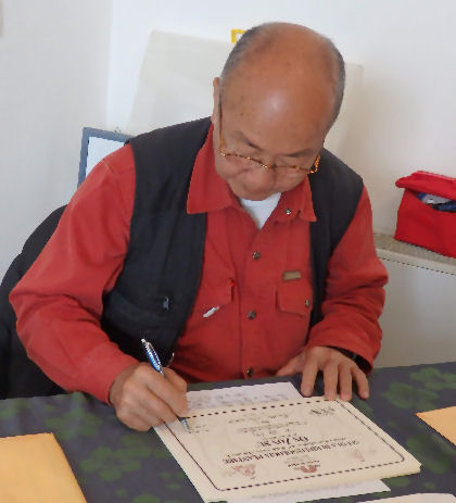 Maestro Ming sigla gli attestati dei diplomi della On Zon Su School durante un corso di riflessologia plantare che forma riflessologi esperti.