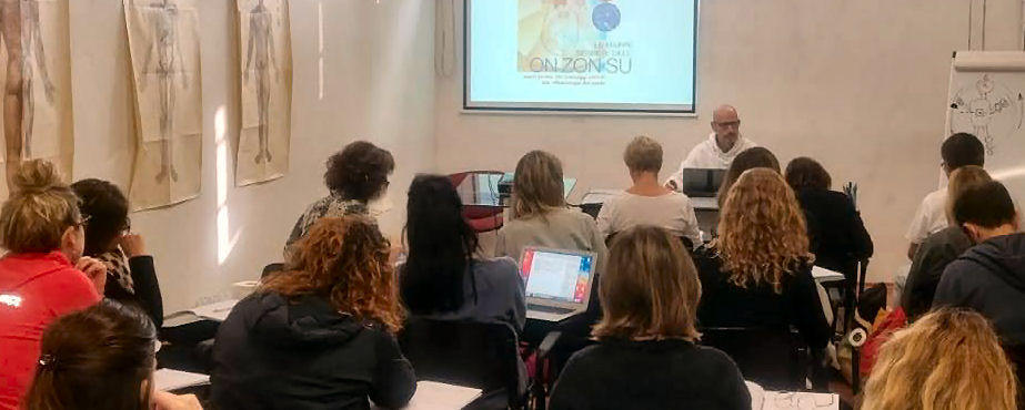 Immagine raffigurante un gruppo di studenti della On Zon Su School durante una lezione teorica, con l'insegnante, al corso di riflessologia plantare. Anche a Roma si sviluppano i corsi