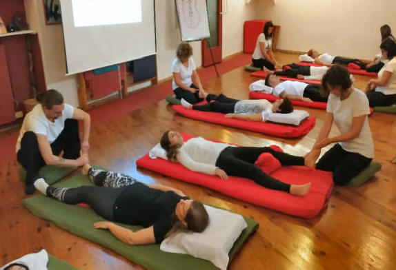 Gruppo di studenti della on zon su school eseguono tecniche di on zon su durante un corso di riflessologia plantare per riflessologi.